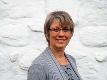 Porträt einer lächelnden Frau mit Brille.