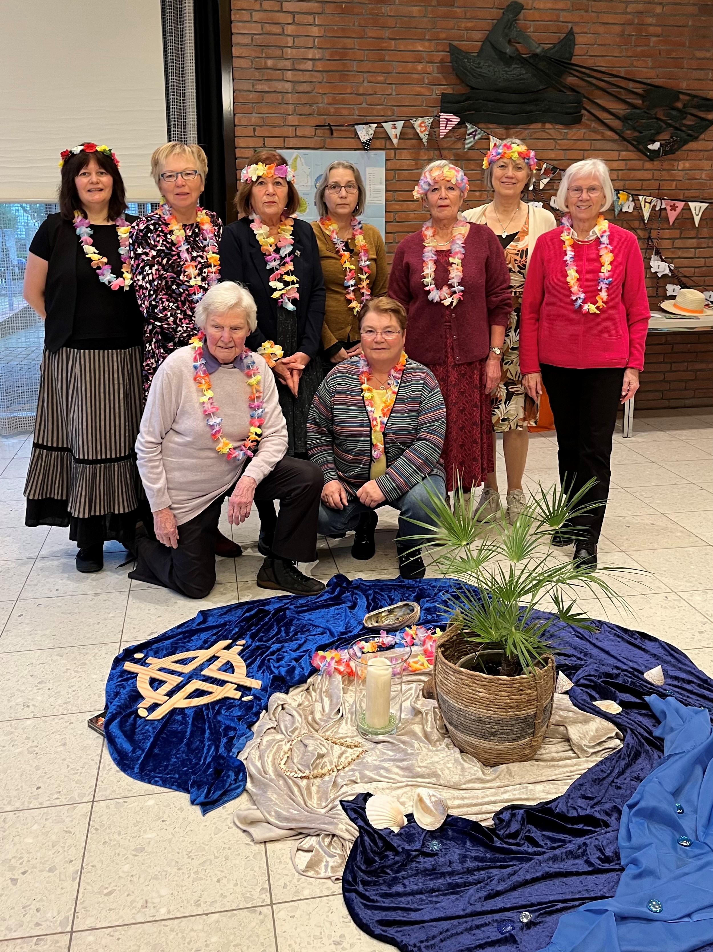 Gruppe von Frauen in festlicher Kleidung mit Blumenketten.